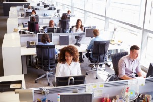 Team of customer services and support staff working at desks in a busy open plan office