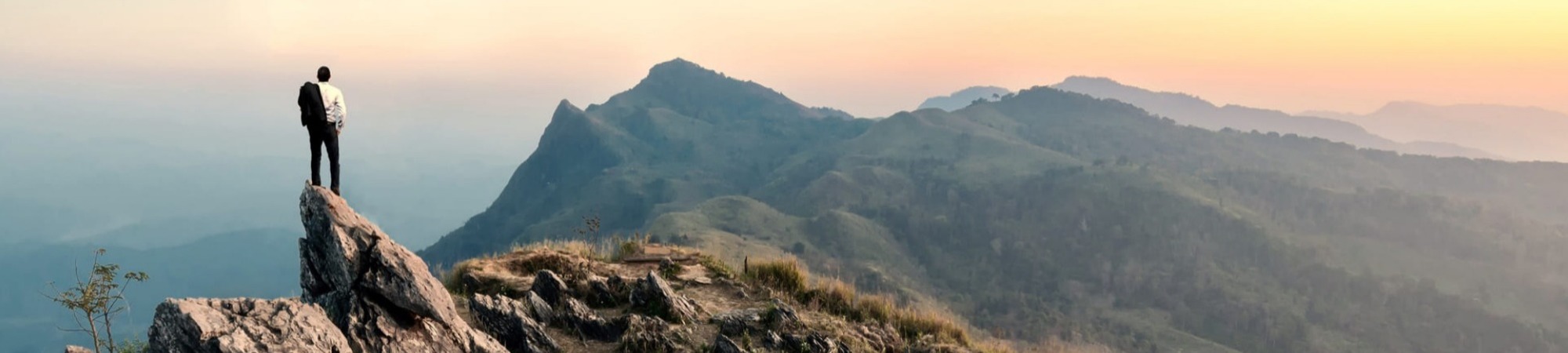 Businessman hike on the peak of rocks mountain at sunset, success, winner, leader concept