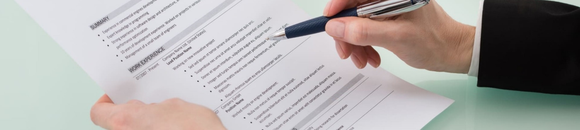 Close-up of a person holding a CV and reviewing with pen